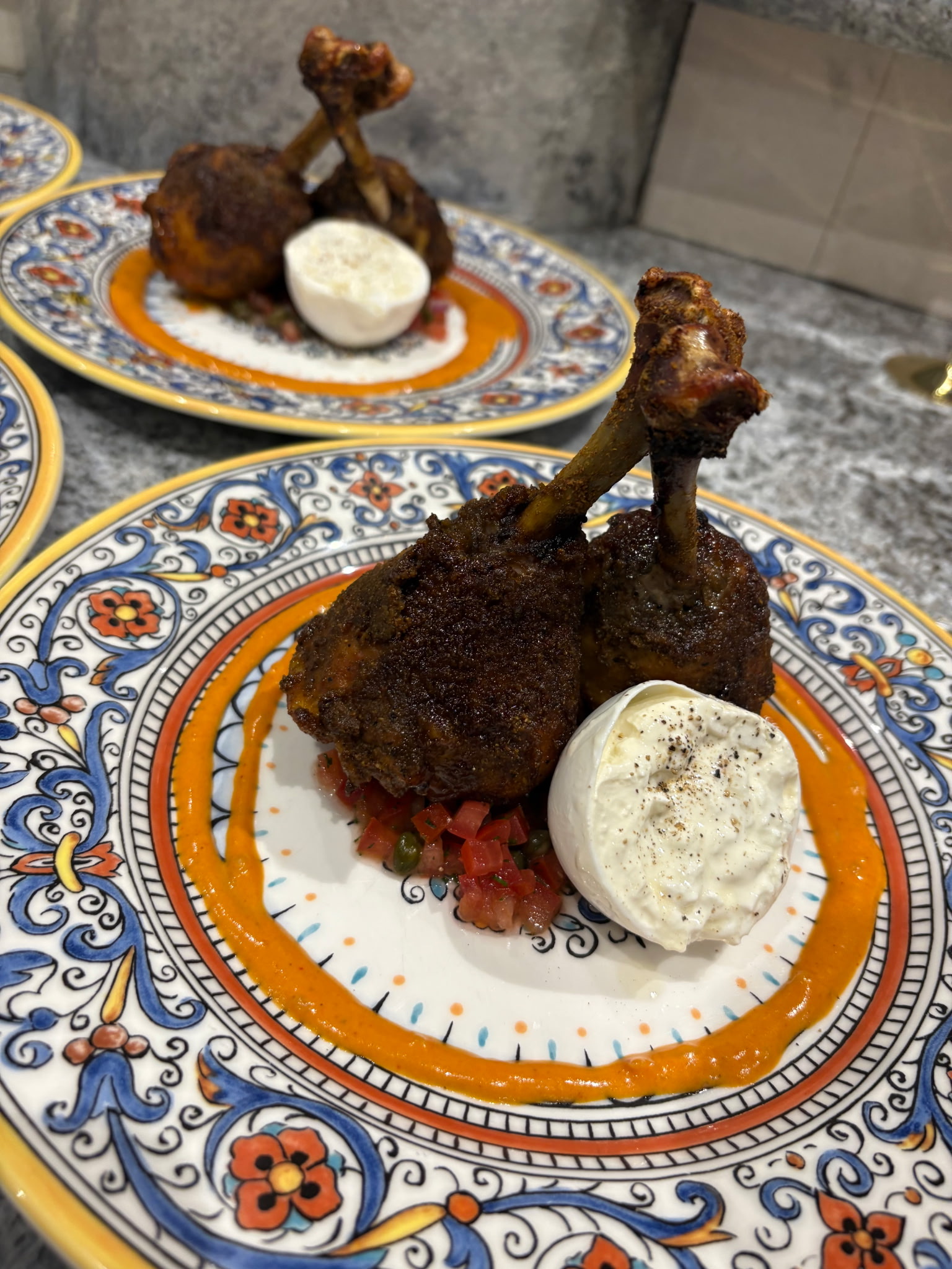 Crisp chicken drumsticks with creamy cheese and colorful sauce, served on patterned plates